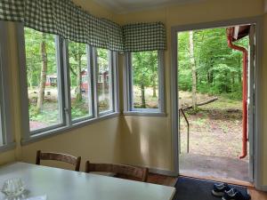 a dining room with a table and three windows at Ormanäs Stugby in Höör