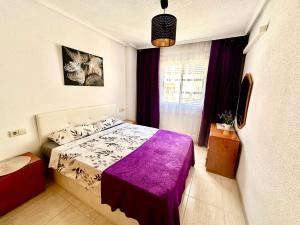a bedroom with a bed with a purple blanket at La Loma 72 in Torrevieja