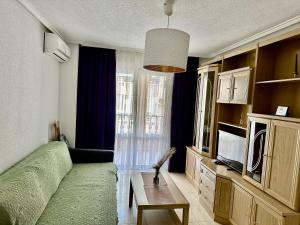 a living room with a green couch and a television at La Loma 72 in Torrevieja