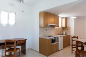 a kitchen with wooden cabinets and a table and a table and chairs at Alekos Studios Artemonas in Artemonas