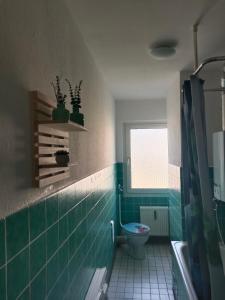 a bathroom with a toilet and a window and green tiles at Nette Kuschelige Terrassen Wohnung in Bochum