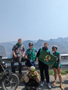 een groep mensen die poseren voor een foto met een vlag bij Og homes in Ha Giang