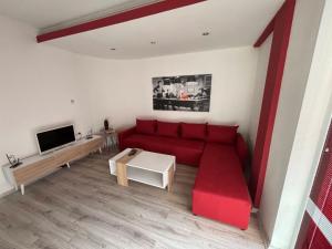 a living room with a red couch and a tv at Ako odam vo Bitola in Bitola