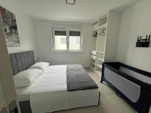a white bedroom with a bed and a book shelf at Residence Doli Pool in Vrsi +8 photos