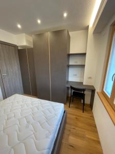 a bedroom with a bed and a desk and a window at Trilocale nel centro storico di Bormio in Bormio