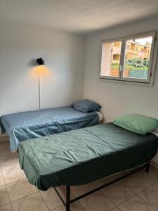 two beds in a room with a window at Appartement proche de la mer in Sainte-Marie-la-Mer