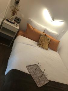 una camera da letto con un grande letto bianco con cuscini arancioni di Chez Julien à 2 pas de La Défense a Puteaux