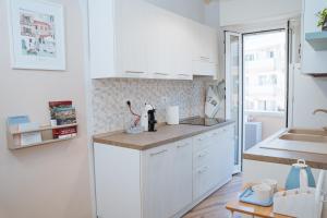 a white kitchen with white cabinets and a sink at Next stop Ostia in Lido di Ostia