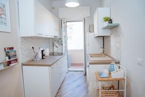 a small kitchen with white cabinets and a wooden floor at Next stop Ostia in Lido di Ostia +19 photos