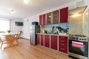 a kitchen with red cabinets and a stainless steel refrigerator at VillaGiewont in Kościelisko