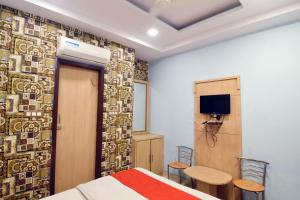 a bedroom with a bed and two chairs and a tv at Hotel Maharaja Palace in Alīgarh