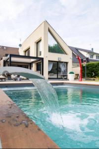 une piscine avec une fontaine à eau devant une maison dans l'établissement Villa avec piscine 35 min de Paris, à Étiolles