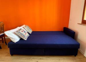a blue bed in a room with an orange wall at Casa Giù in Cecina