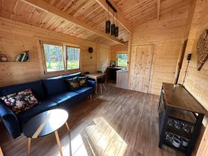 a living room with a blue couch in a log cabin at Stary Las Siemczyno in Siemczyno