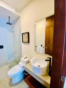 a bathroom with a white toilet and a sink at Tuane Tulum Deluxe in Tulum