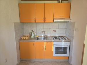 a small kitchen with orange cabinets and a sink at Apartman Majetić in Seliste Dreznicko