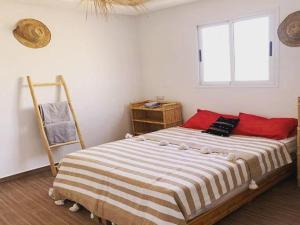 a bedroom with a bed with red pillows and a window at Wsurfmaroc in Agadir