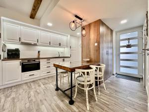 a kitchen with white cabinets and a table and chairs at LAKE MOMENTS - Ruby Garden Apartment in Balatonszemes