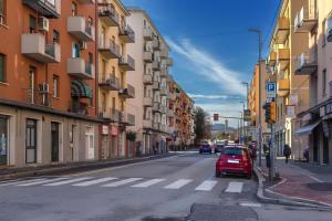 a red car parked on a city street with buildings at Bologna Travel Suite in Bologna