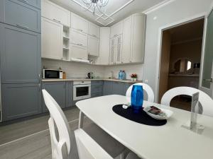 eine Küche mit weißen Schränken sowie einem weißen Tisch und Stühlen in der Unterkunft Трехкомнатные бизнес апартаменты в ЖК Заман in Atyrau + 5 Fotos