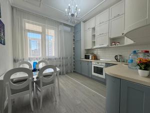 eine Küche mit weißen Schränken und einem Tisch und Stühlen in der Unterkunft Трехкомнатные бизнес апартаменты в ЖК Заман in Atyrau