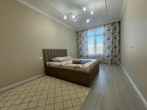 ein Schlafzimmer mit einem Bett und einem Fenster in der Unterkunft Трехкомнатные бизнес апартаменты в ЖК Заман in Atyrau