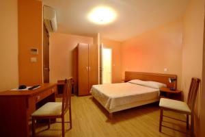 a bedroom with a bed and a desk and chairs at Hotel le Dauphin in Ajaccio