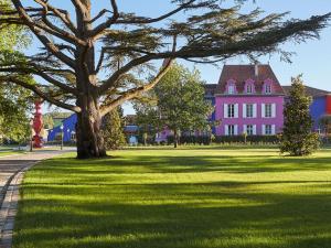 een roze huis met een boom in het gras bij Le Stelsia Resort in Saint-Sylvestre-sur-Lot