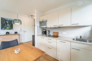 a kitchen with white cabinets and a wooden table at Am Sonneneck - DreiGipfelblick Fewo6 mit Sauna in Ruhpolding