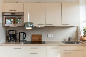 a kitchen with white cabinets and a sink at Am Sonneneck - DreiGipfelblick Fewo6 mit Sauna in Ruhpolding