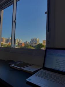 a laptop computer sitting on a desk next to a window at Apto no Centro próximo a UFN - Garagem in Santa Maria