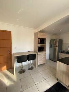 a kitchen with a desk and a refrigerator at Apto no Centro próximo a UFN - Garagem in Santa Maria