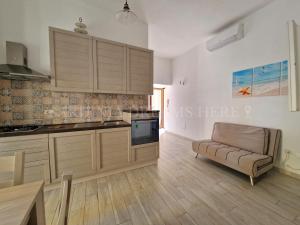 a kitchen with wooden cabinets and a couch in a room at Casa Gemma a 300 m dalla spiaggia Rena Bianca in Santa Teresa Gallura