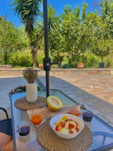 una mesa con un bol de fruta y vasos de zumo en Riverside apartments, en Lefkada