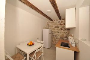 a small kitchen with a table and a white refrigerator at Old stone house Danka in Kotor