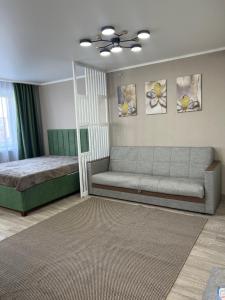 ein Wohnzimmer mit einer Couch und einem Bett in der Unterkunft Люкс 1-комнатная квартира in Balqasch