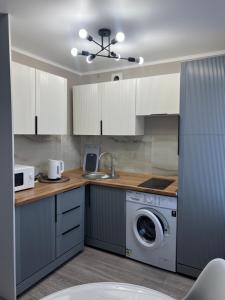 eine Küche mit weißen Schränken und einer Waschmaschine in der Unterkunft Люкс 1-комнатная квартира in Balqasch