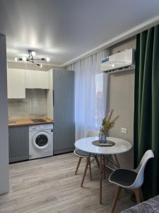 eine kleine Küche mit Tisch und Stühlen in einem Zimmer in der Unterkunft Люкс 1-комнатная квартира in Balqasch