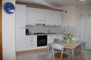 a kitchen with white cabinets and a table and a clock at Casa Vacanze Da Nico in Matera