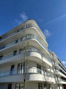 a white building with a balcony on the side of it at Apartament Rubin by Eleganckie Apartamenty Sianożęty - 100 metrów od plaży, wysoki standard in Sianozety
