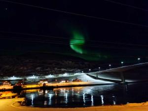 an aurora over a body of water at night at apartament by the sea in Havøysund