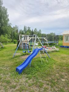 a playground with a blue slide in a field at Vanha myllärin torppa in Sulkava +2 photos