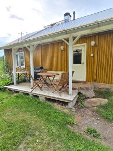 a cabin with a table and chairs on a porch at Vanha myllärin torppa in Sulkava