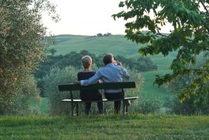 para siedząca na ławce patrząca na wzgórza w obiekcie Podere Spedalone w mieście Pienza