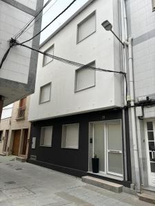 a white and black building with a street light at Apartamentos turísticos Demar in O Grove