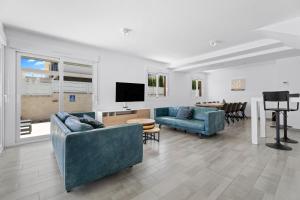 a living room with two blue couches and a television at Casa Bos Flamingo Pool and Jacuzzi in Puerto Marino