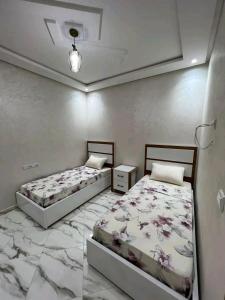 2 bedden in een kamer met marmeren vloeren bij مارتيل حي احريق in Martil