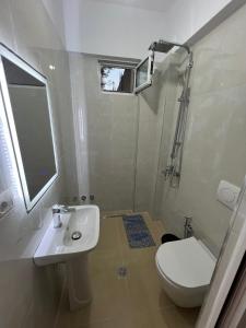 a bathroom with a sink and a toilet and a mirror at Anna Rooms in Sarandë +3 photos