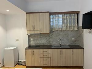 a kitchen with wooden cabinets and a sink at Anna Rooms in Sarandë