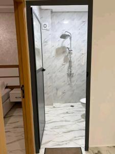 een douche met een glazen deur in een badkamer bij مارتيل حي احريق in Martil +6 foto's